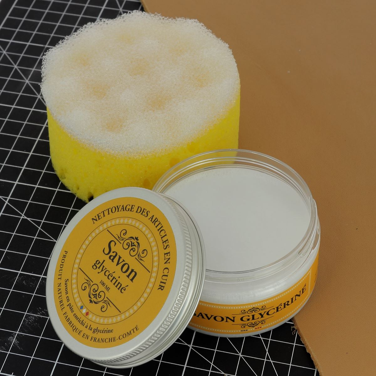 Savon en pâte enrichi à la glycérine pour nettoyer le cuir, présenté dans un emballage blanc, pour l'entretien du cuir.