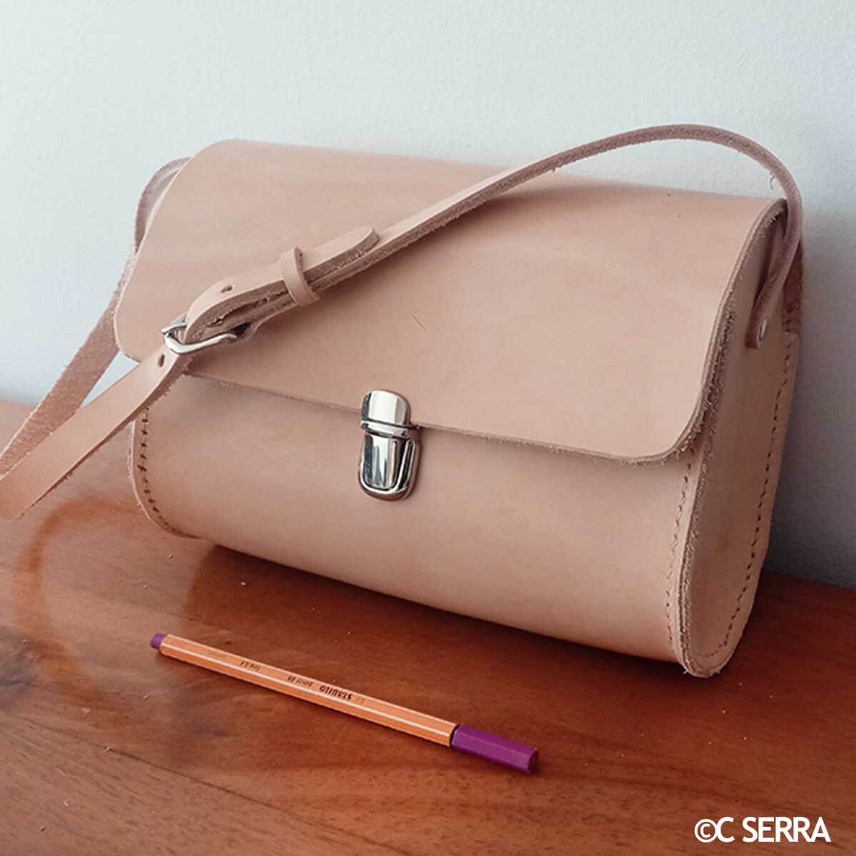 Fermeture de cartable TUCK en métal de 20x36mm pour accessoires, porté sur un sac en cuir végétal naturel.